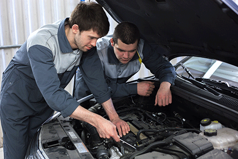 Two technicians inspecting components in an engine bay